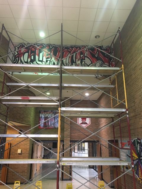 A scaffolding system to the ceiling where a mural is being painted