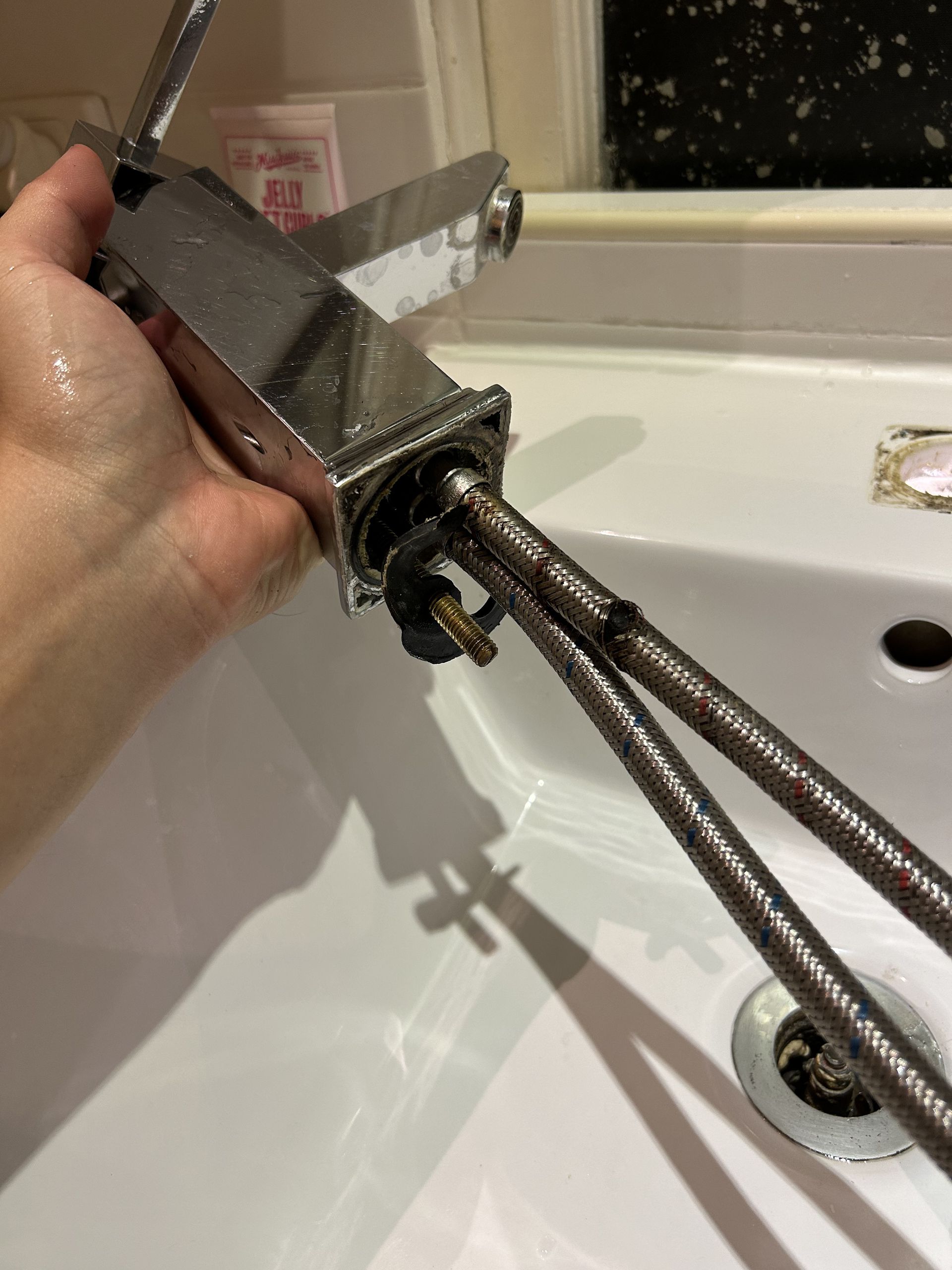 Person Using a Wrench to Tighten a Flexible Hose Connected to a Toilet Tank in a Bathroom — No. 2 Plumbing In Kenmore, QLD