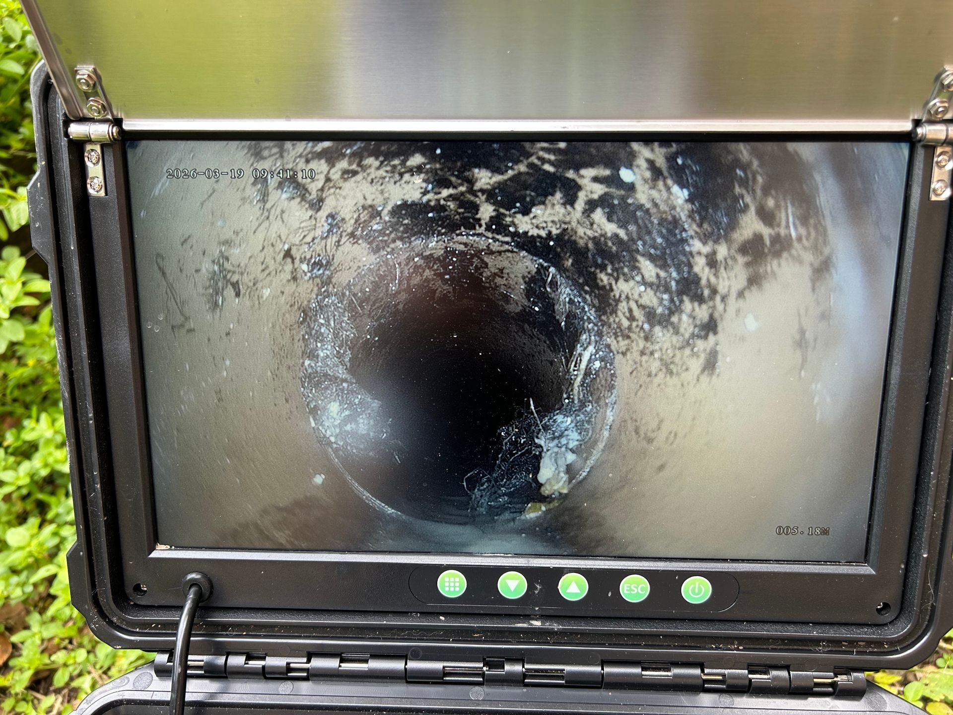 A portable screen displaying a camera feed from inside a dark, grimy pipe during a sewer inspection — No. 2 Plumbing in Kenmore, QLD