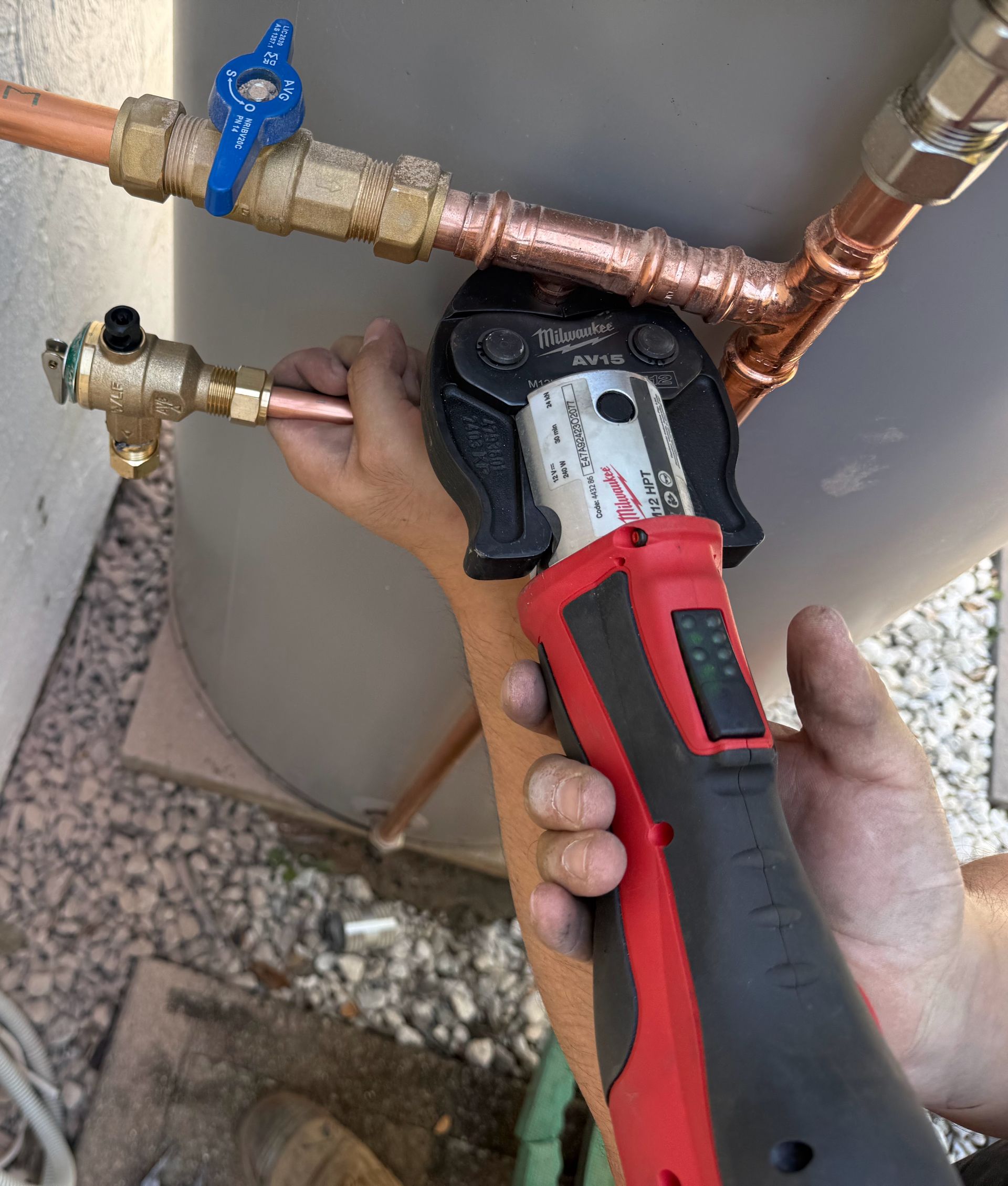 A person using a red and black press tool to connect copper pipes near a water heater. — No. 2 Plumbing In Kenmore, QLD