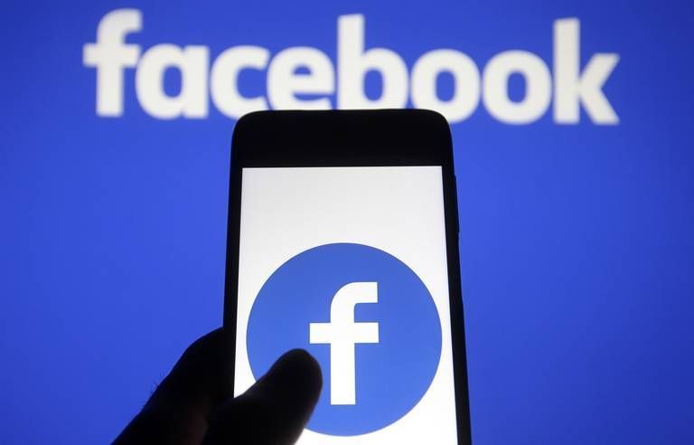 a person is holding a cell phone in front of a facebook logo