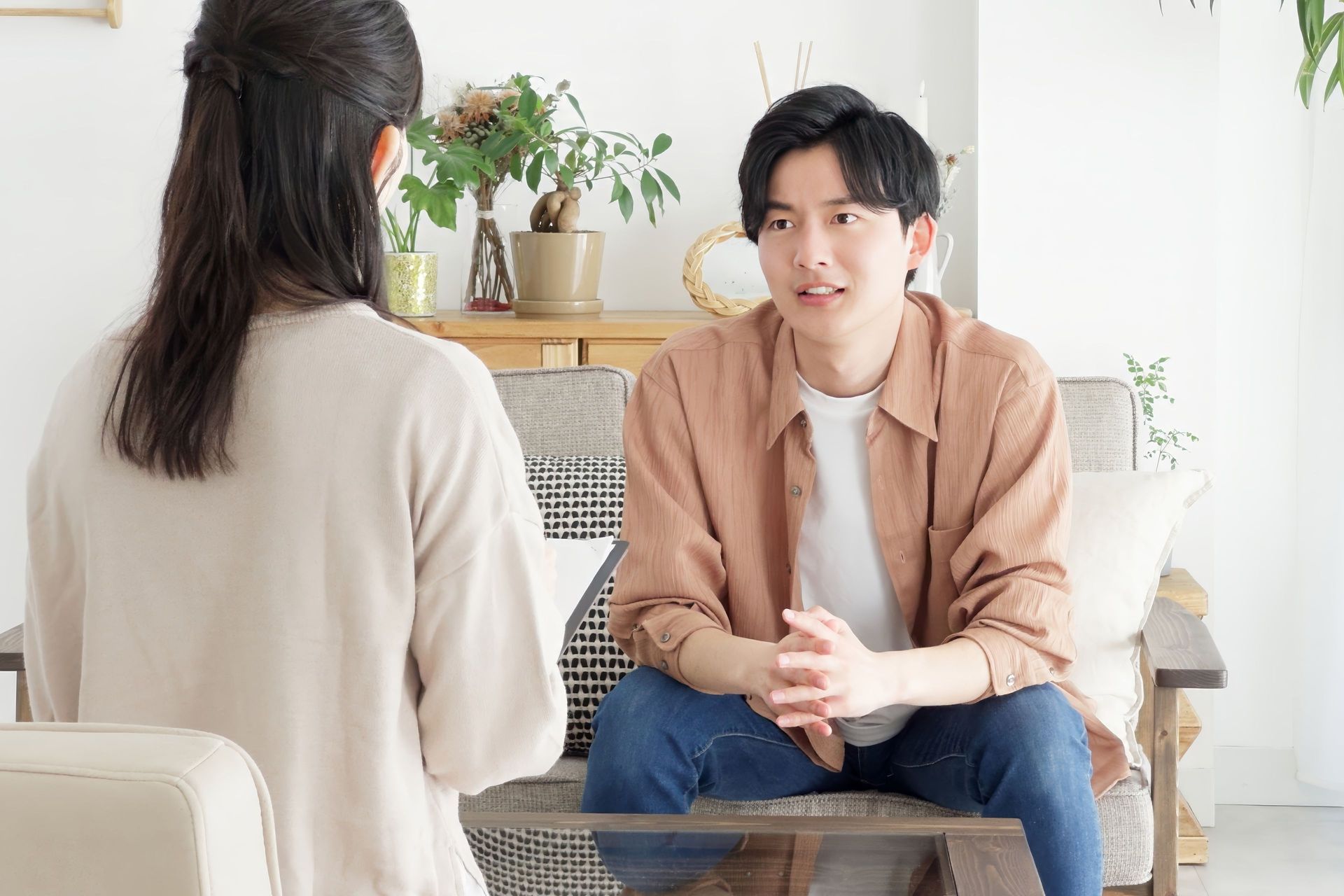 Man and woman in conversation on a couch; indoor setting.