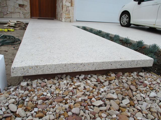 A white car is parked in front of a house
