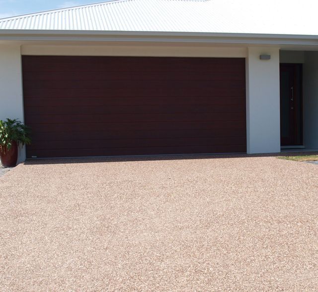 A brown garage door is sitting in front of a white house