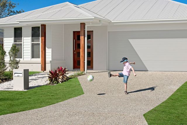 A child is kicking a soccer ball in front of a white house