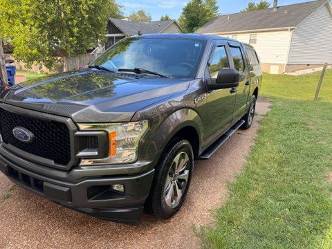 A gray ford f150 truck is parked in front of a house.
