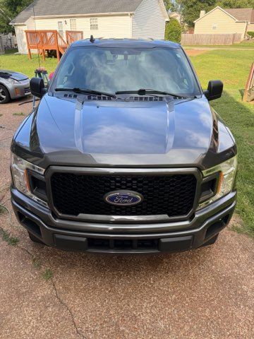 A ford f150 is parked in a driveway in front of a house.