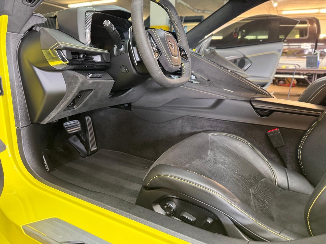The interior of a yellow sports car with the door open.