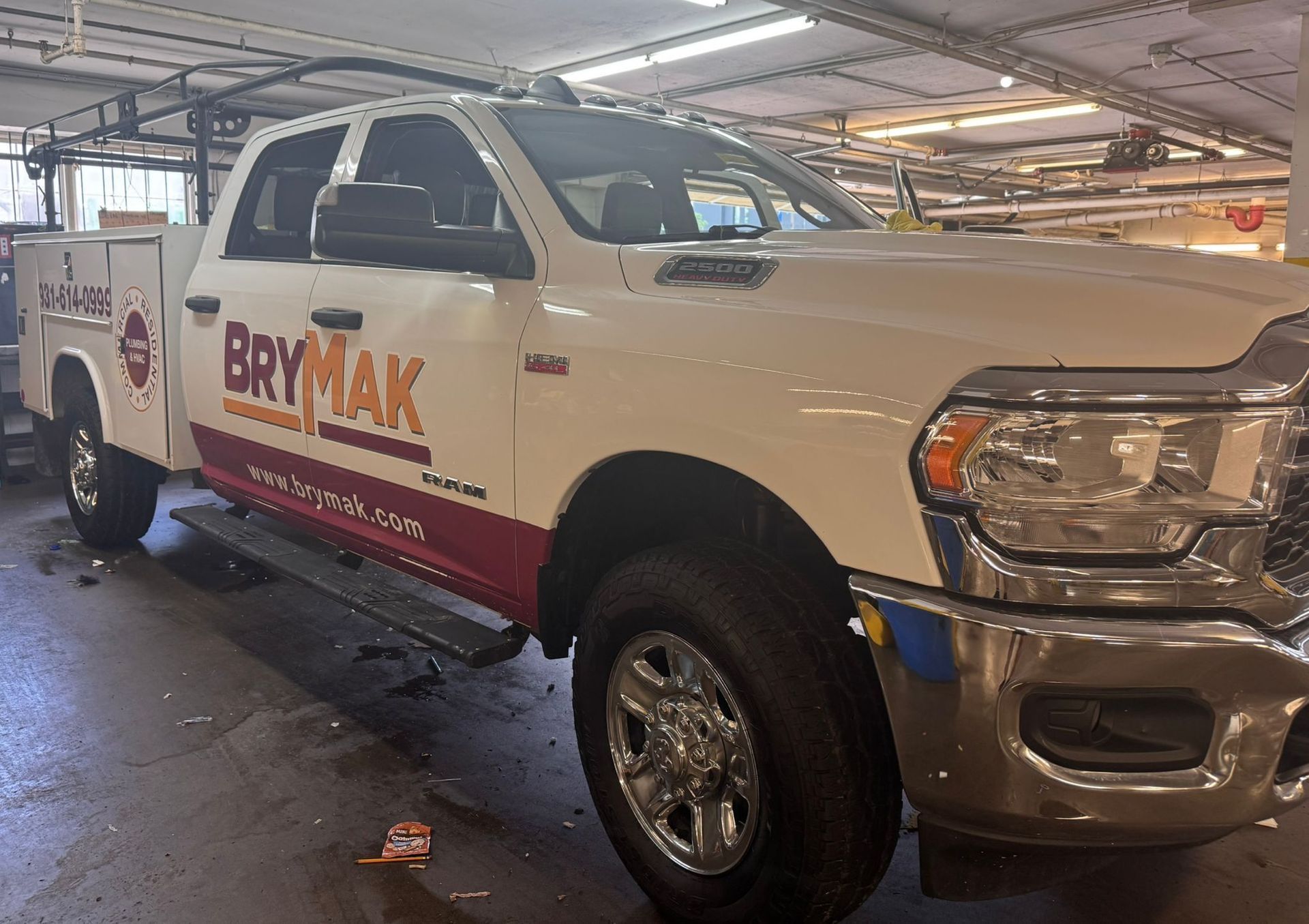 A white truck with the word brymak on the side is parked in a garage.