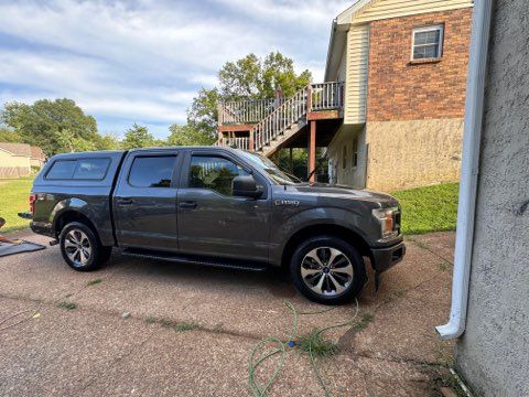 A gray pickup truck is parked in front of a brick house.