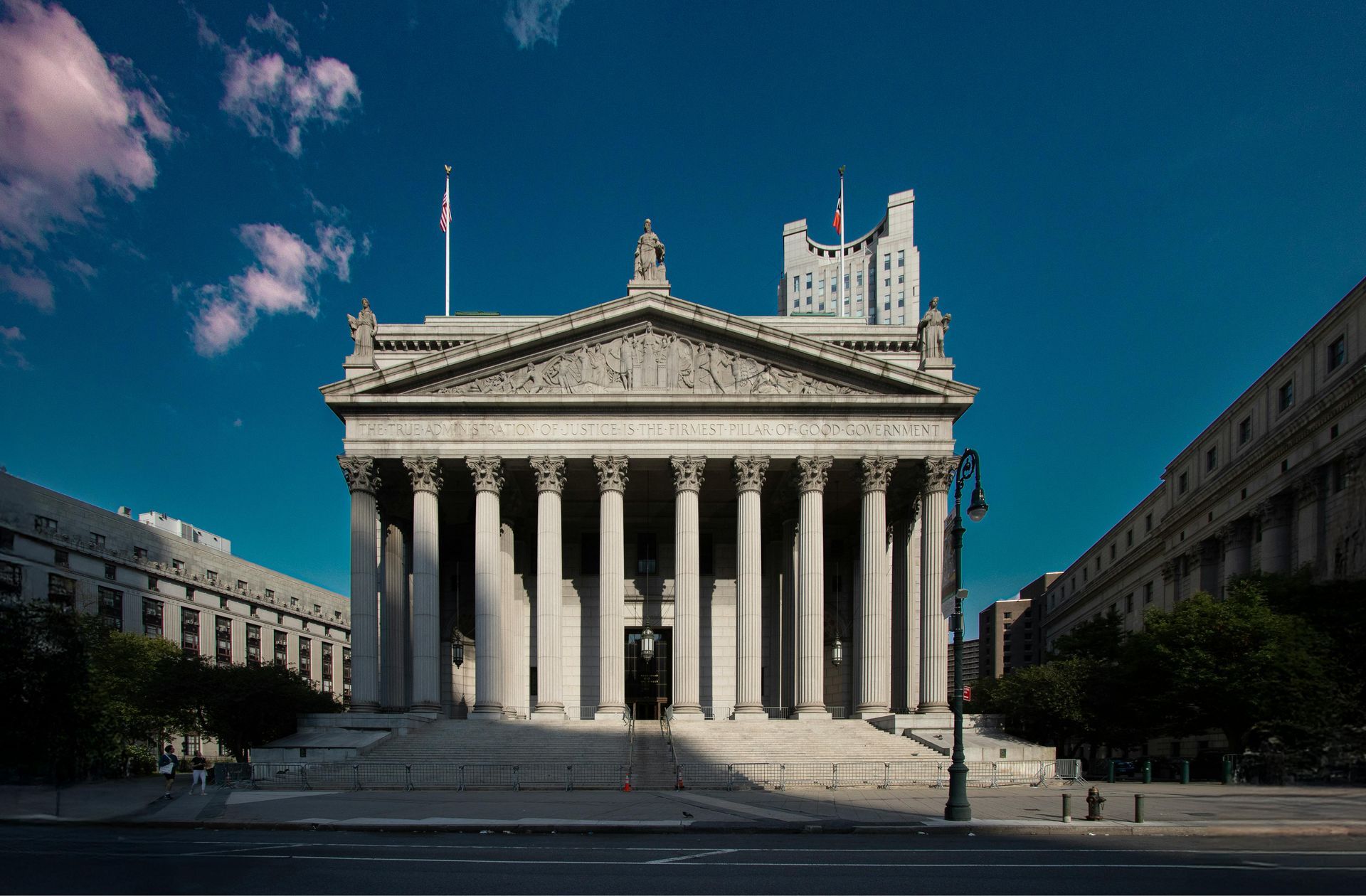 Classical temple with tall columns under a clear blue sky, viewed from a wide plaza