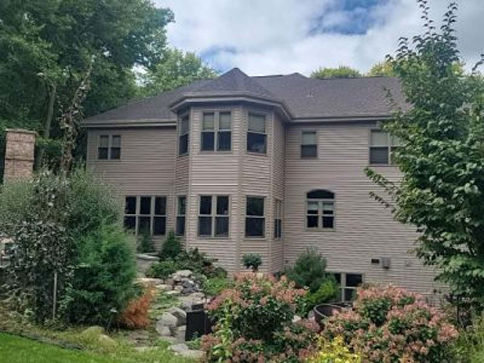 A large house with a lot of windows is surrounded by trees and bushes
