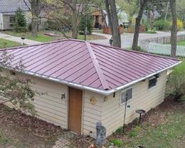 An aerial view of a small house with a red metal roof.
