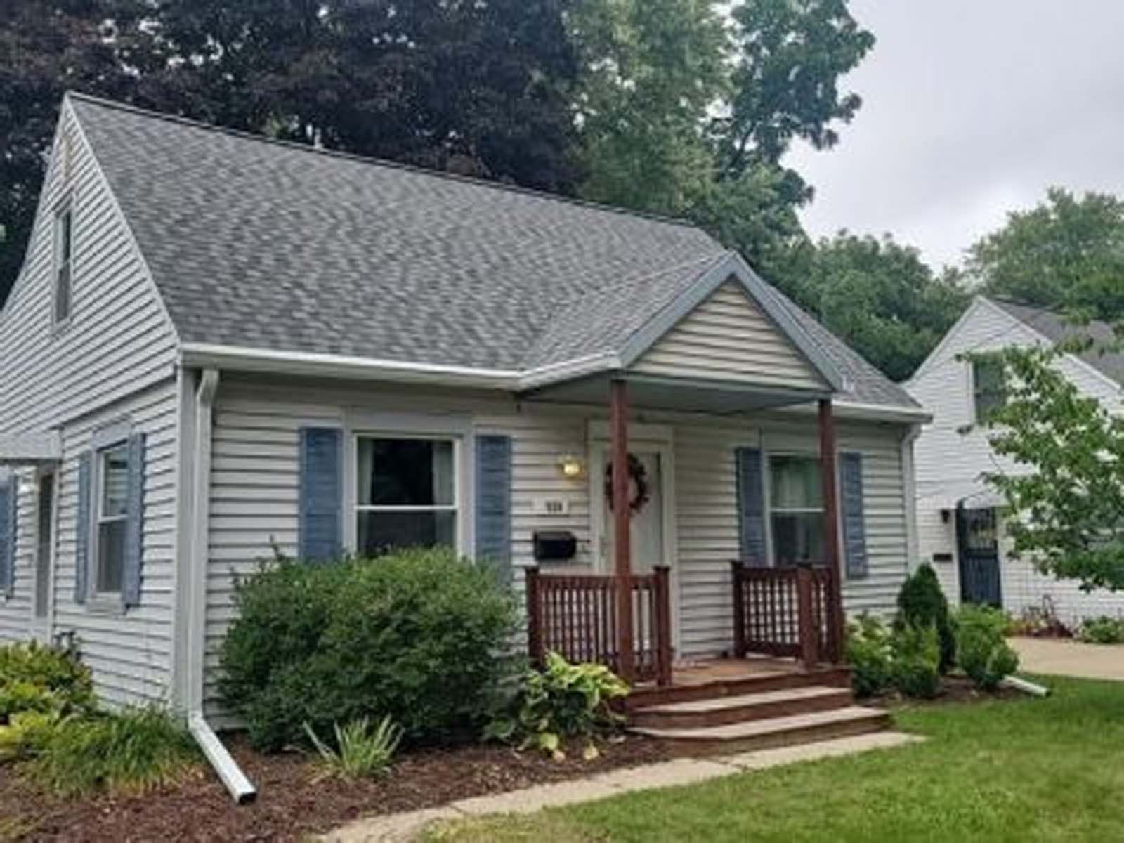 A small white house with blue shutters and a porch.