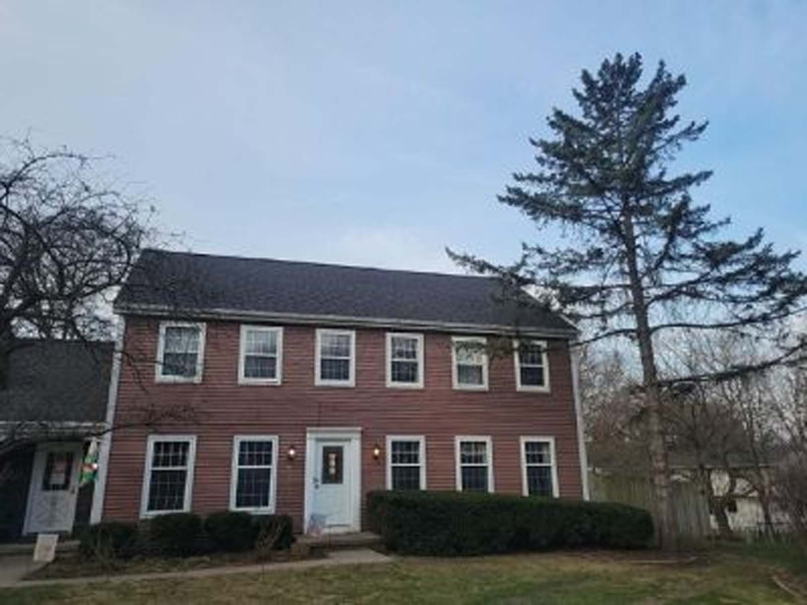 A large brick house with a tree in front of it