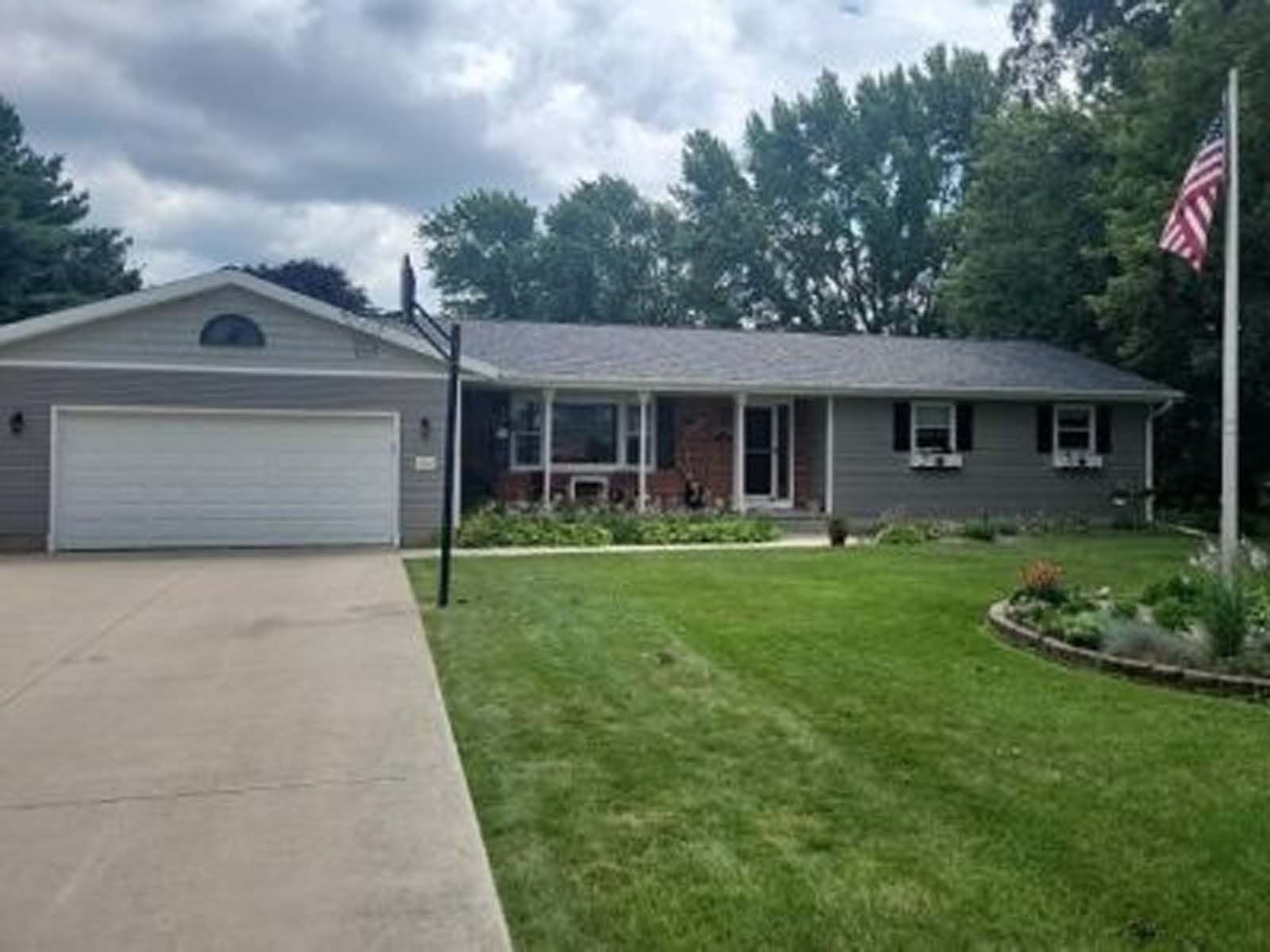 A house with a large garage and a flag in front of it.