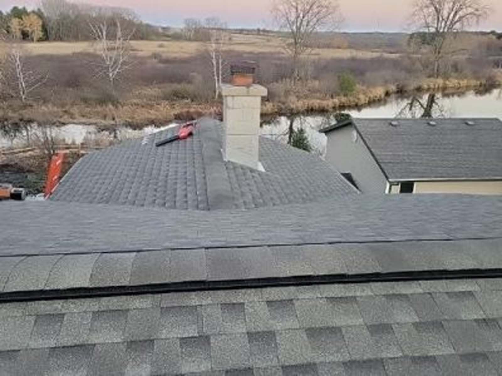 A roof with a chimney on it and a river in the background.