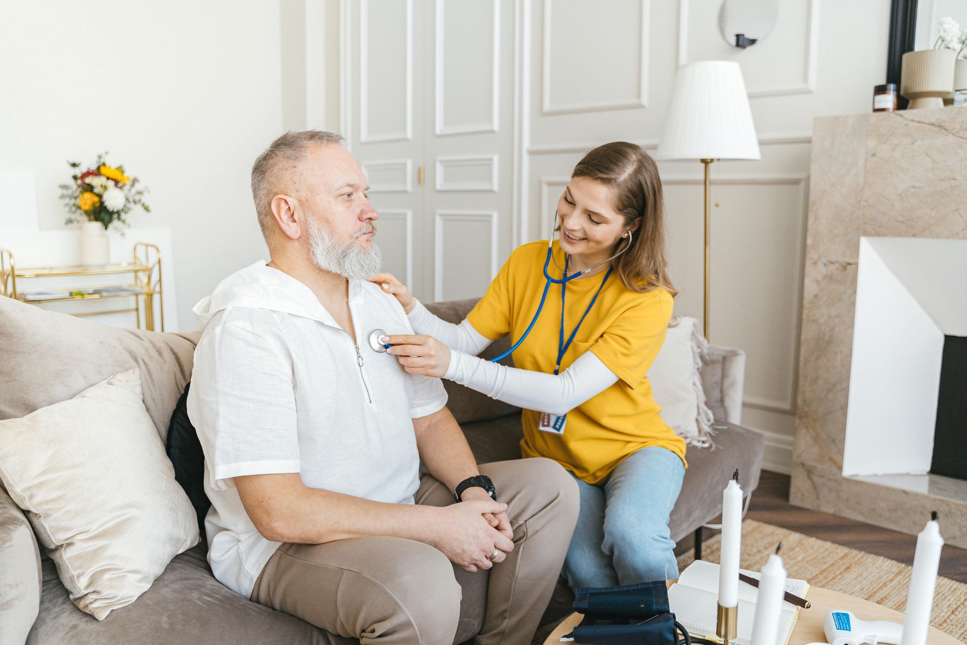 A nurse is examining an elderly man 's chest with a stethoscope.