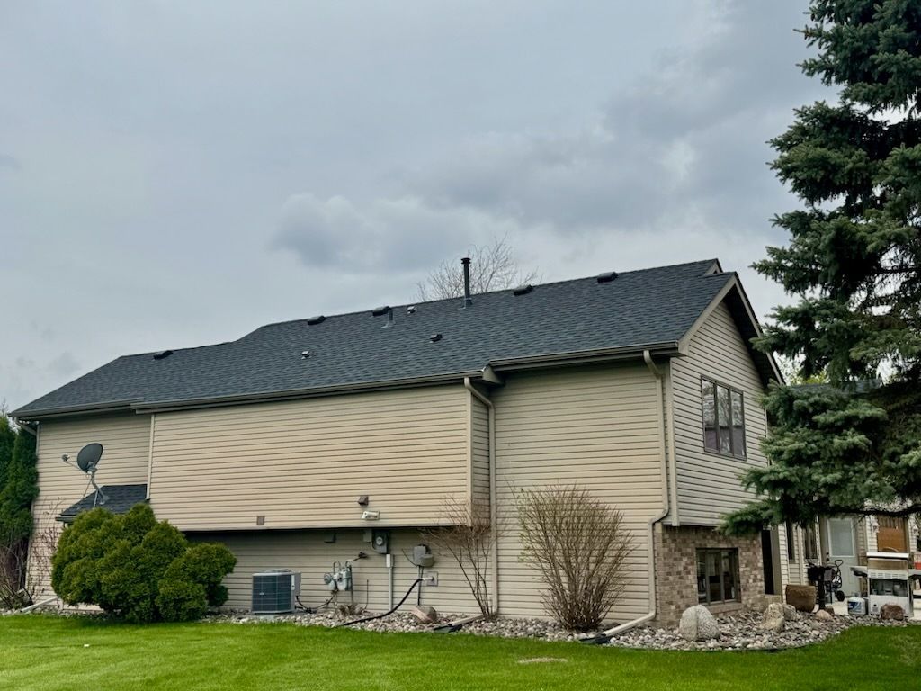 A large house with a black roof is sitting on top of a lush green lawn.