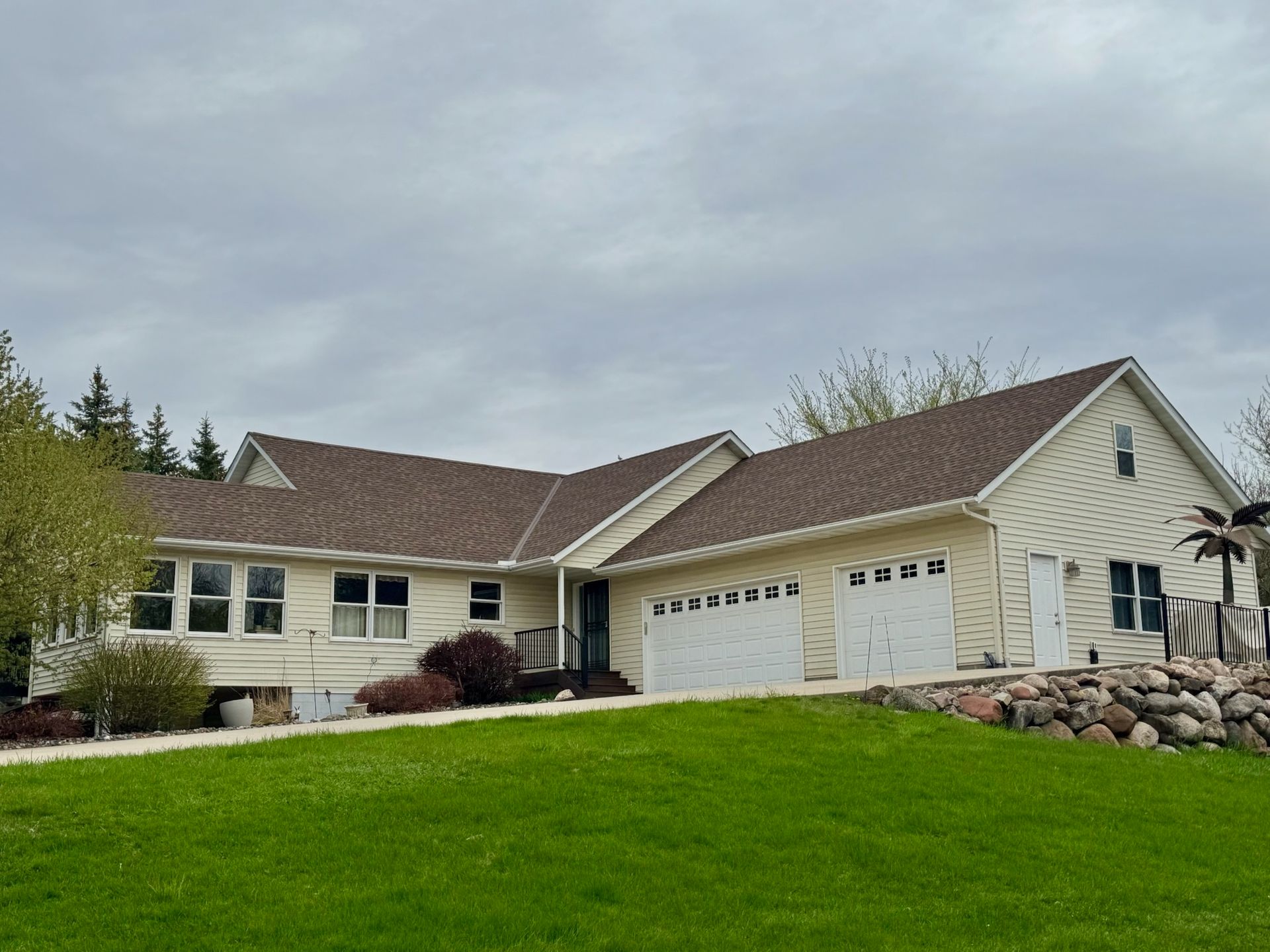 A house with a brown roof and a large lawn in front of it