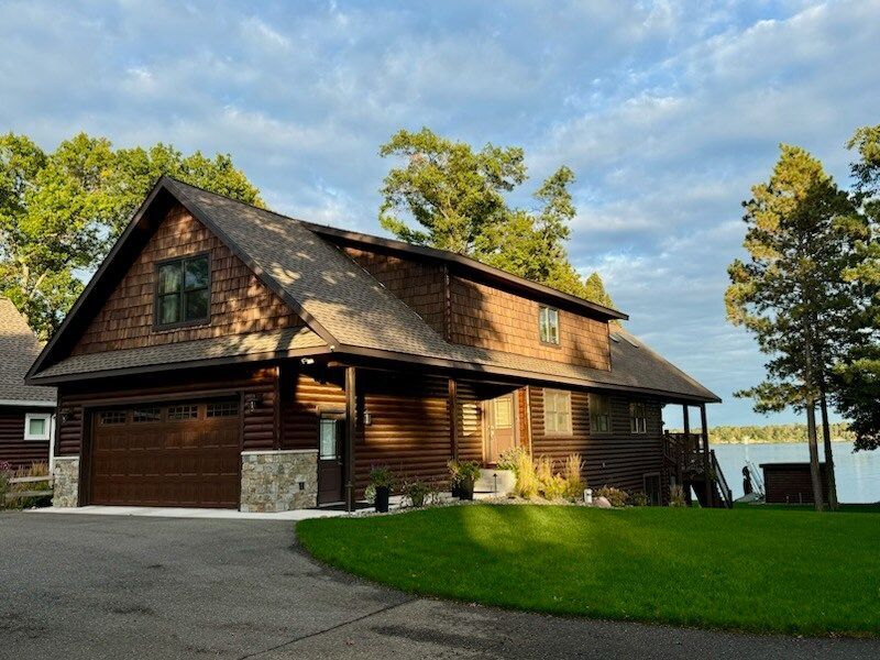 A large wooden house with a large garage next to a lake