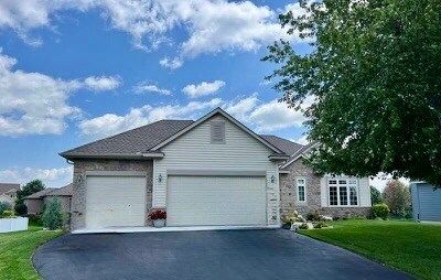 A house with two garage doors and a tree in front of it.