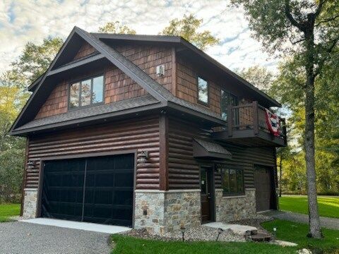 A large wooden house with a black garage door and a balcony.