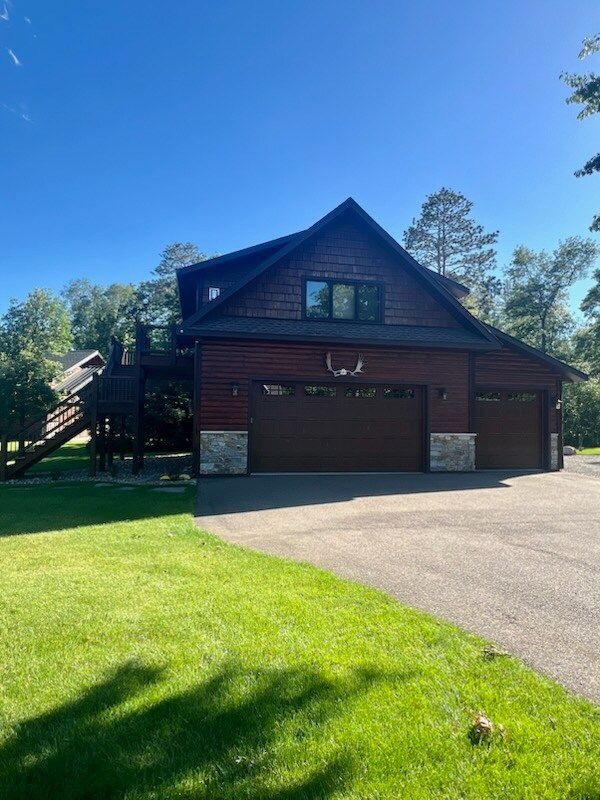 A large wooden house with a large garage and a deck.