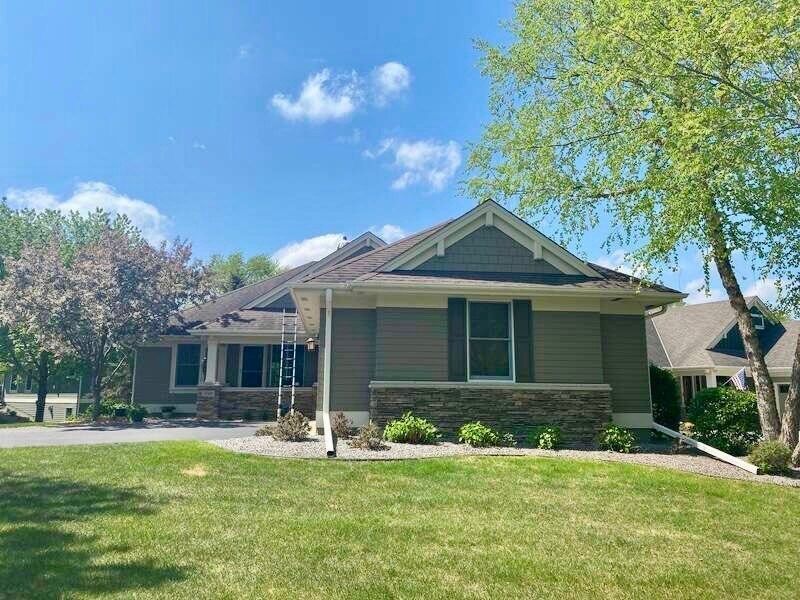 A house with a ladder in front of it is sitting on top of a lush green lawn.