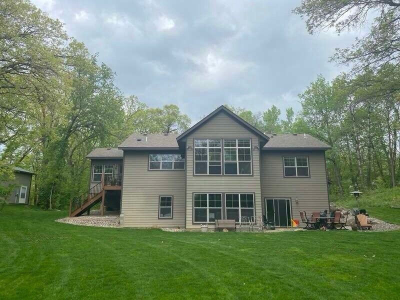 A large house with a lot of windows is sitting on top of a lush green hill.