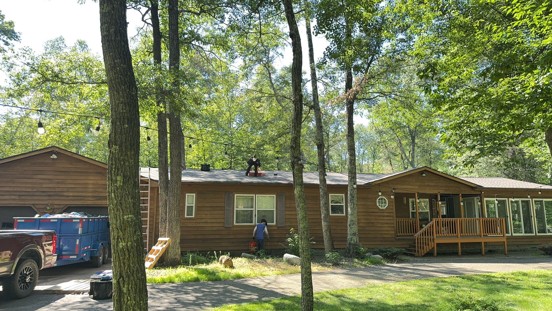 A mobile home is surrounded by trees and a truck is parked in front of it.