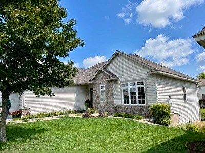 A house with a lush green lawn and a tree in front of it.