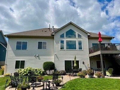 The back of a large house with a large deck and patio.
