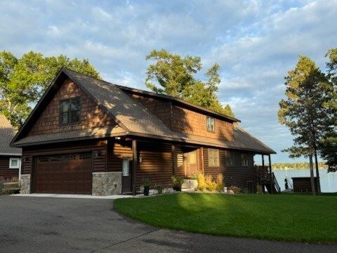 A large wooden house with a large garage is next to a lake