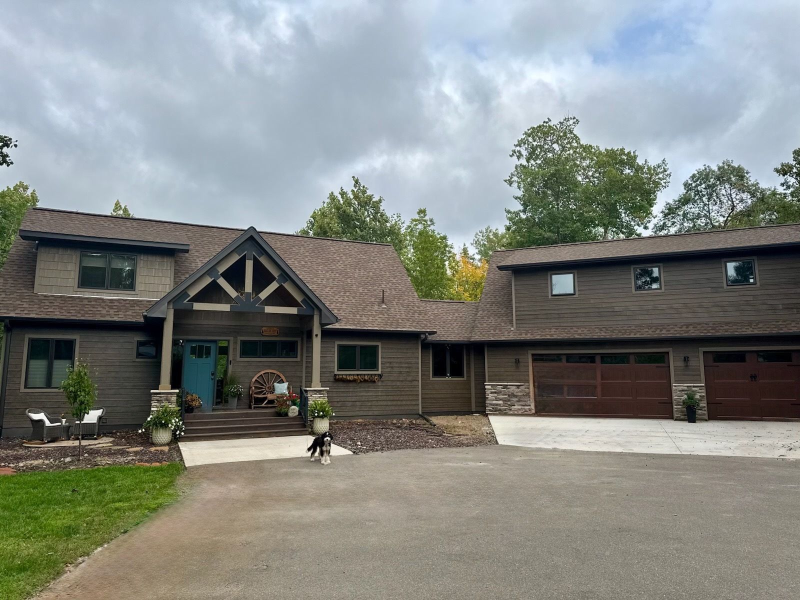 A large house with a garage and a driveway is surrounded by trees.