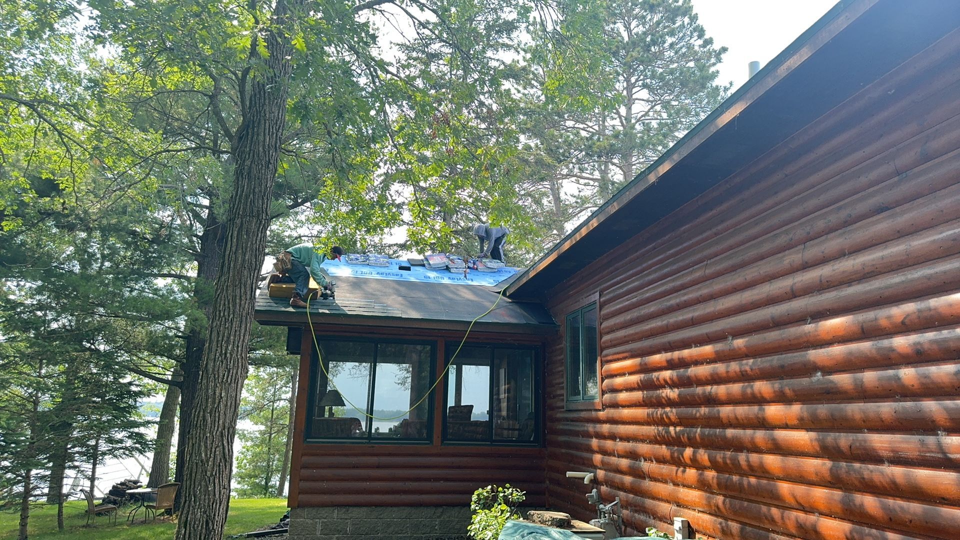 A man is working on the roof of a log cabin.