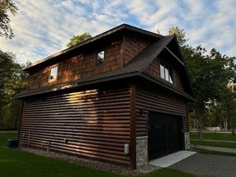 A large log cabin with a garage and a roof