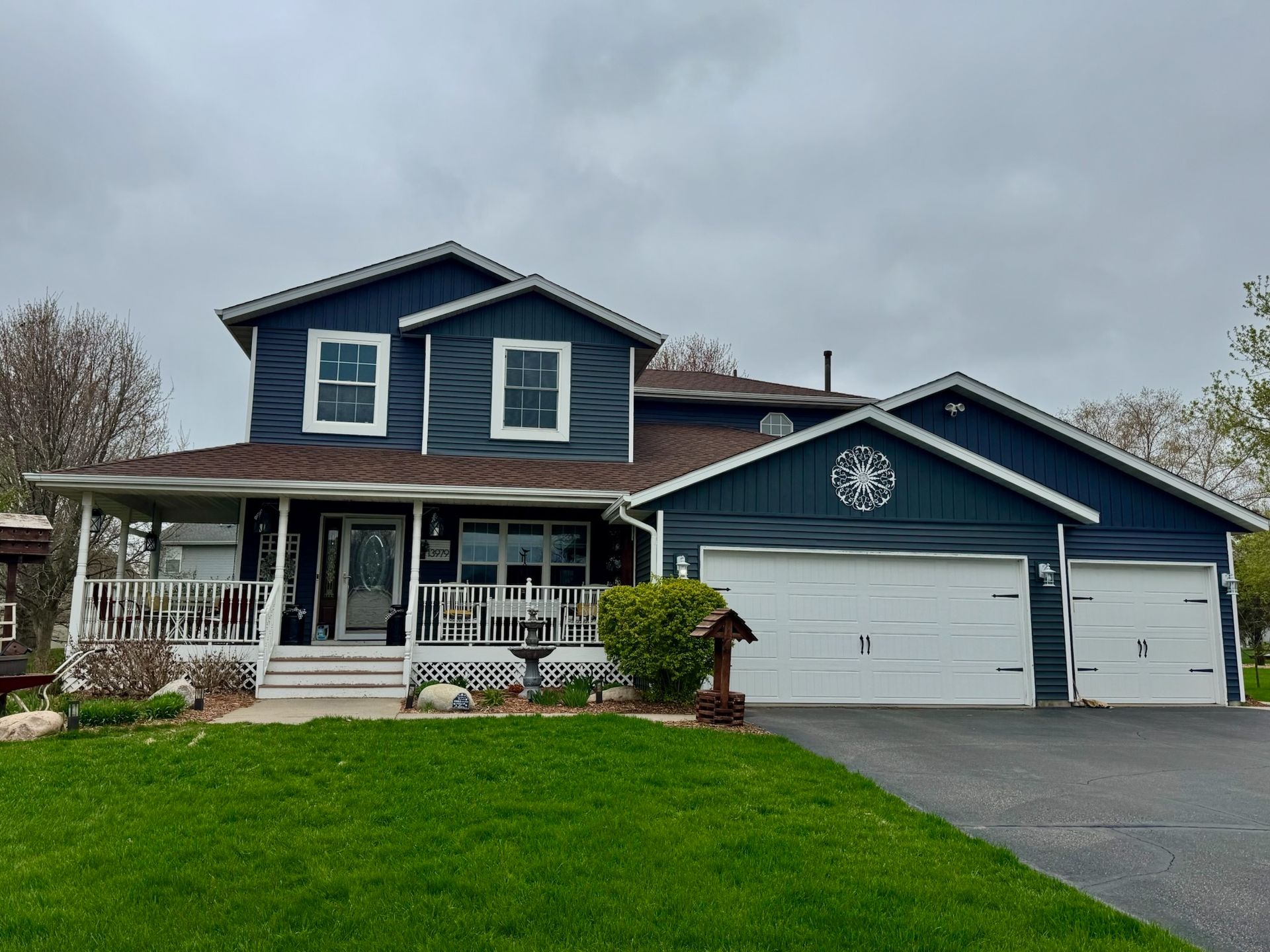 A large blue house with a white garage door and a porch.