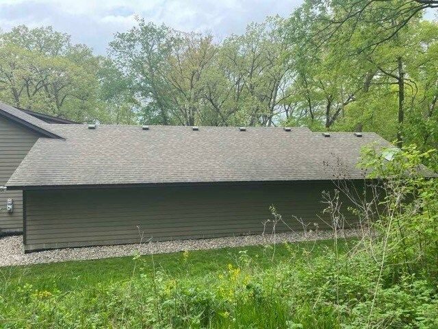 A house with a roof that is surrounded by trees and grass.