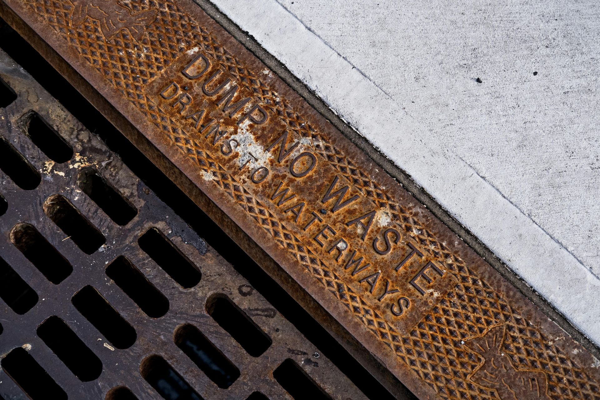 A rusty manhole cover with the words dumping waste written on it