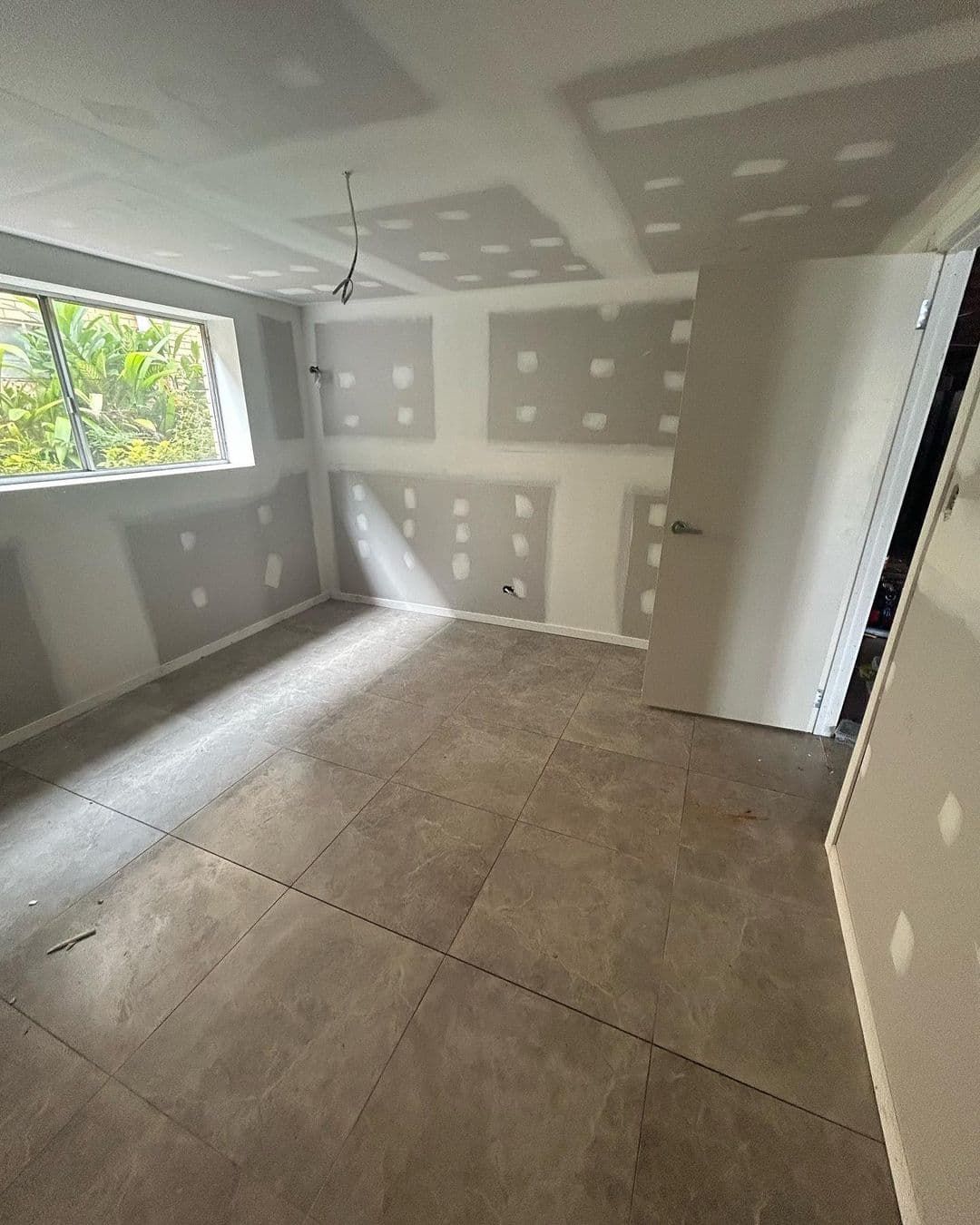 An Empty Room With A Tiled Floor And A Window — Jordan Building & Construction Pty Ltd in Ascot, QLD