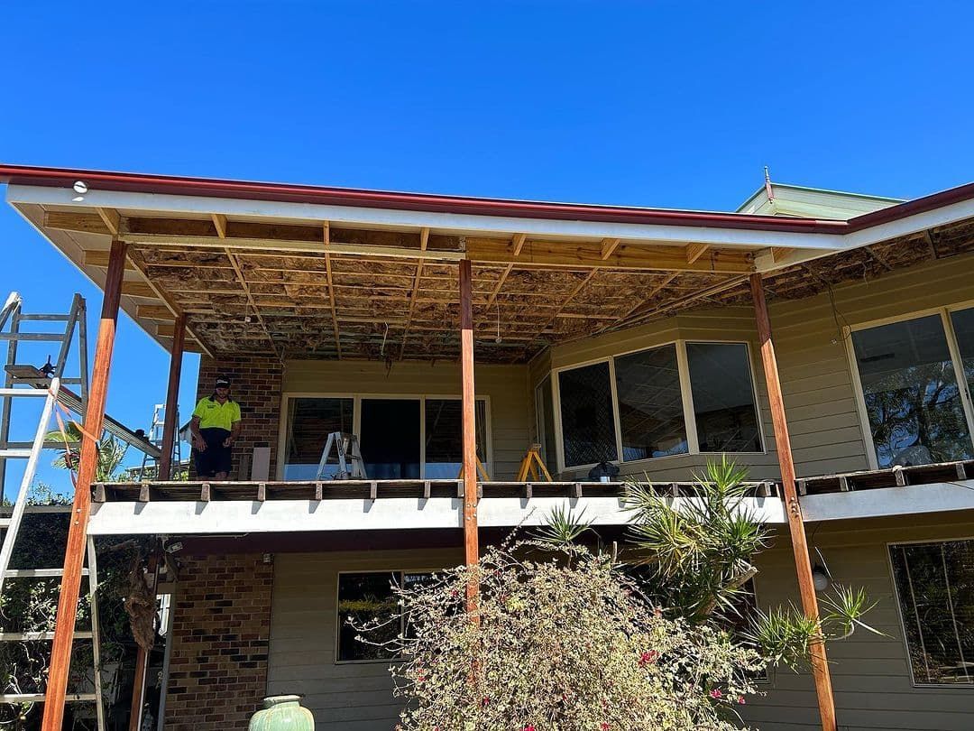 A Man Is Standing On A Porch Of A House Under Construction — Jordan Building & Construction Pty Ltd in Ascot, QLD