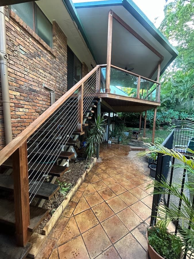 A Brick House With A Wooden Deck And Stairs Leading Up To It — Jordan Building & Construction Pty Ltd in Ascot, QLD