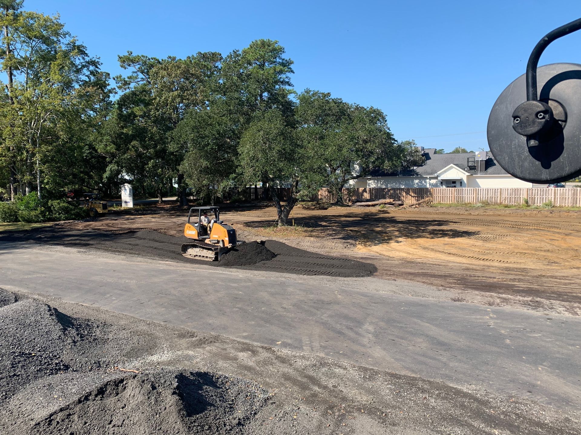 A bulldozer is working on a dirt field in front of a house.