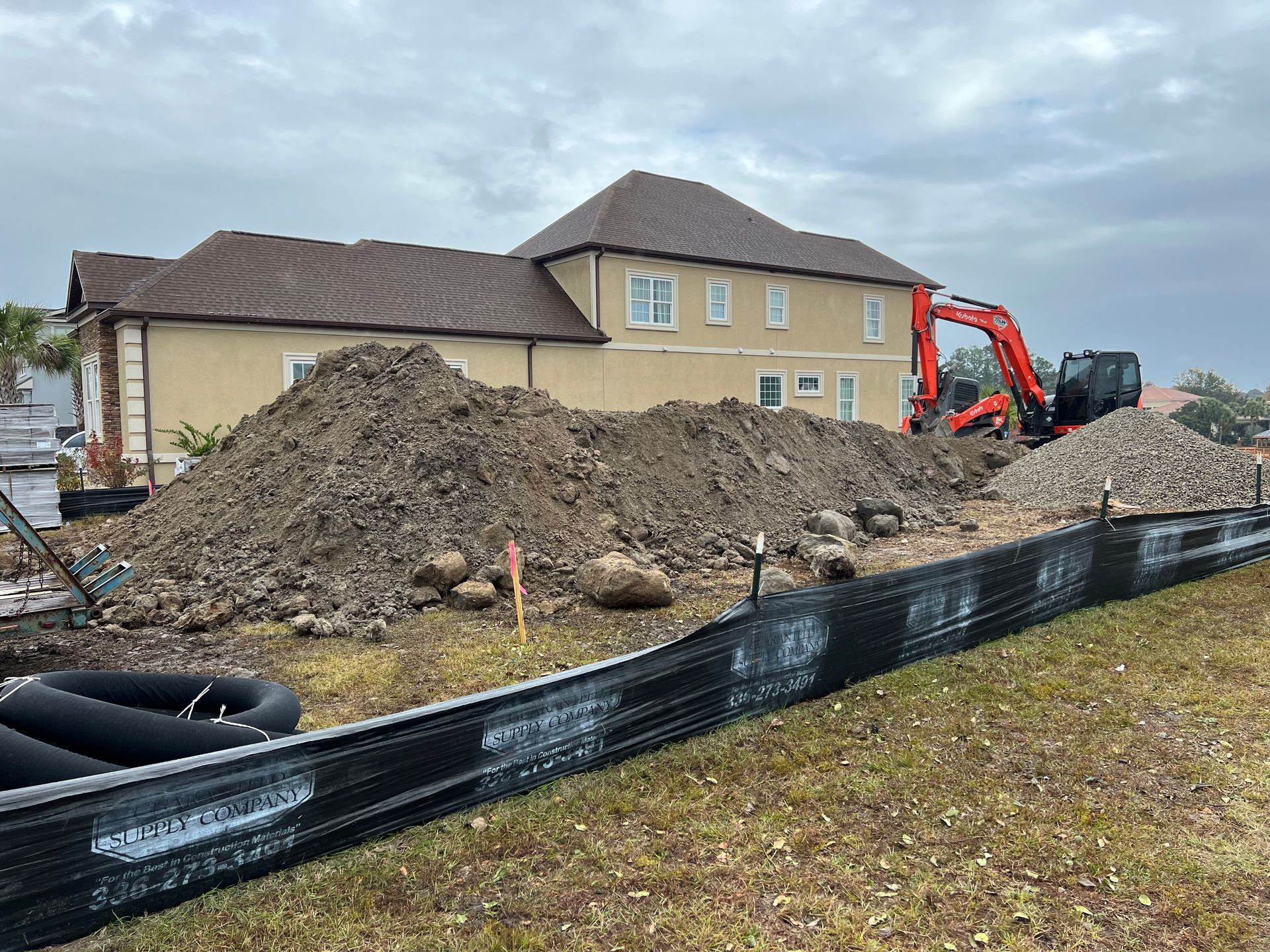 A bulldozer is working on a dirt field in front of a house.