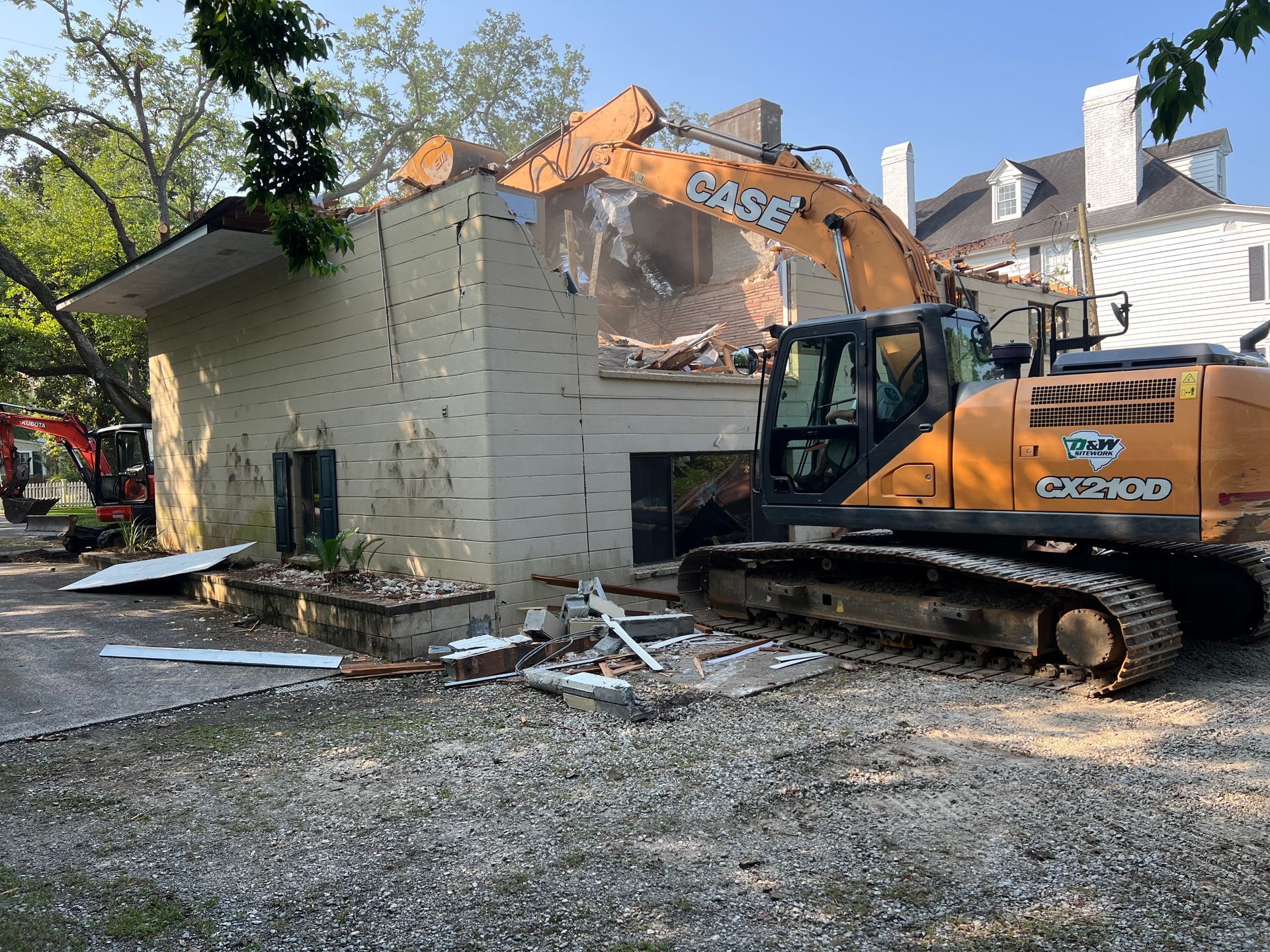 A large excavator is demolishing a brick building.