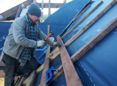 A man is working on a roof with a hammer