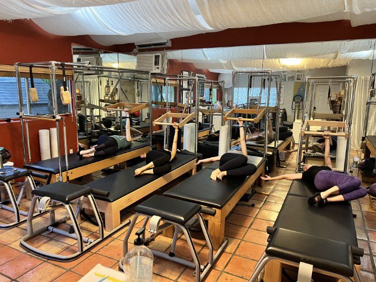 A group of people are doing pilates exercises in a studio