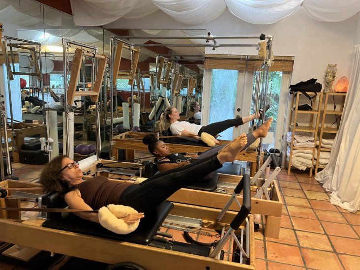 A woman is laying on a pilates machine in a studio.