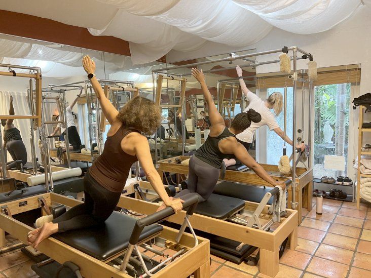 Two women are doing pilates exercises in a studio.